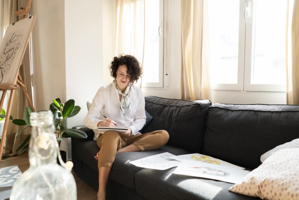 Woman writing on paper on sofa in room